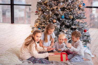 Mutlu çocuklar Noel ağacının yanında eğleniyor.