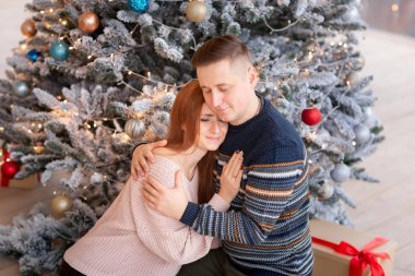 Mutlu çift Noel ağacının yanında eğleniyor.