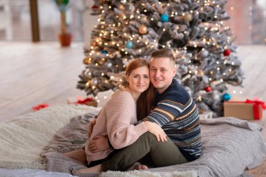Mutlu çift Noel ağacının yanında eğleniyor.