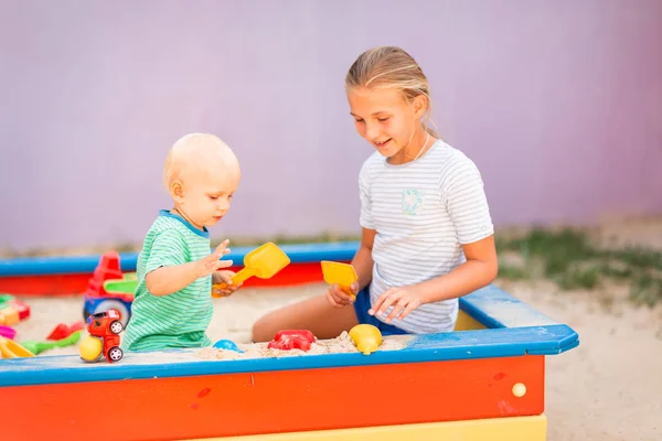 Lindo bebé jugando con su hermana en la caja de arena —  Fotos de Stock