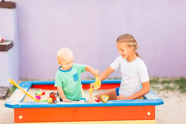 Bébé garçon mignon jouant avec sa sœur dans le bac à sable — Photo