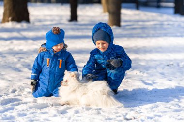 Küçük çocuklar parkta tükürük köpeğiyle oynuyorlar.