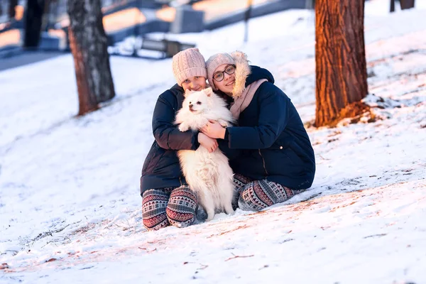 Meninas adolescentes bonitas se divertindo com spitz cão no inverno — Fotografia de Stock