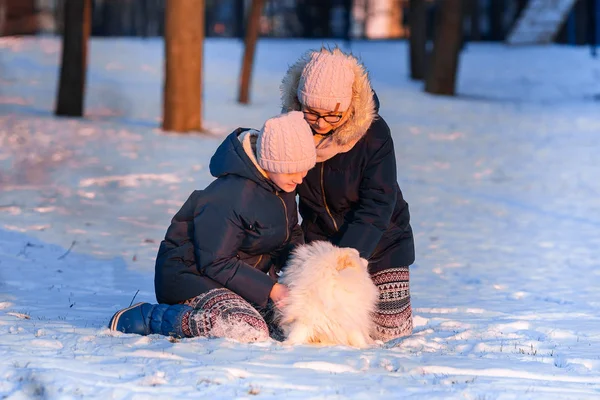 Belle ragazze adolescenti si divertono con il cane spitz in inverno — Foto Stock