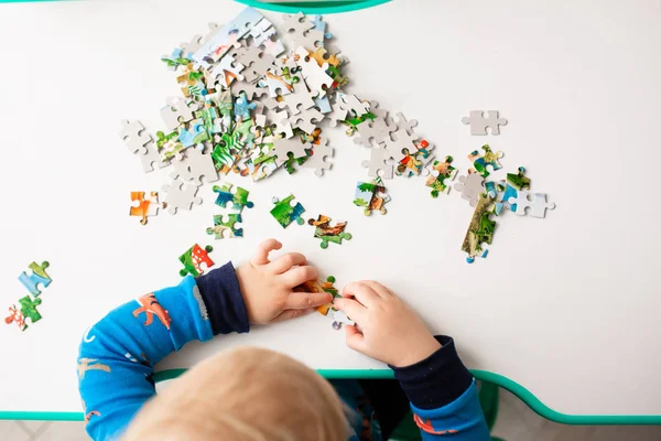 Baby boy solving jigsaw puzzle on the desk — Stock Photo, Image