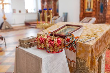 Ortodoks düğün taçları, kilise ikonları, kilise kitapları, masanın üzerindeki İncil.