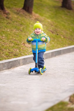 Küçük şirin bir çocuk scooter kullanıyor. Sağlıklı açık hava aktivitesi