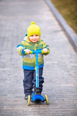 Küçük şirin bir çocuk scooter kullanıyor. Sağlıklı açık hava aktivitesi