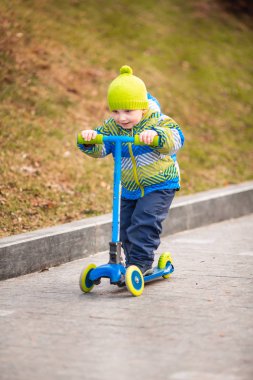 Küçük şirin bir çocuk scooter kullanıyor. Sağlıklı açık hava aktivitesi