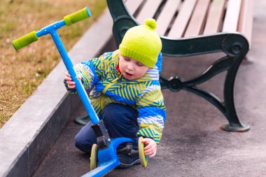 Motosikletten düşen sevimli küçük çocuk. Çocuk scooter kullanırken yaralanmış. Düşen motosiklet kazası. Çocuk ayağa kalkmaya çalışıyor.