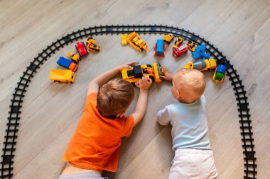 Anaokulu çocukları kağıda resim çiziyorlar, eğitim oyuncaklarıyla oynuyorlar - bloklar, tren, demiryolu, evde veya kreşte araçlar. Anaokulu ve anaokulu oyuncakları. Üst görünüm.