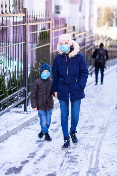在检疫期间 与小男孩一起在街上行走的年轻女子戴着医疗面罩 以保护自己不受污染 细菌和头孢病毒的侵害 Corona Virus Covid Pandemic Protection Concept — 图库照片