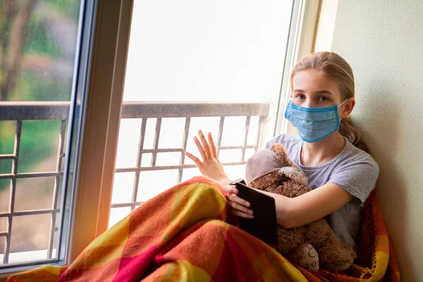 Trauriges Kleines Mädchen Schutzmaske Das Fenster Sitzt Books Oder Tablets — Stockfoto