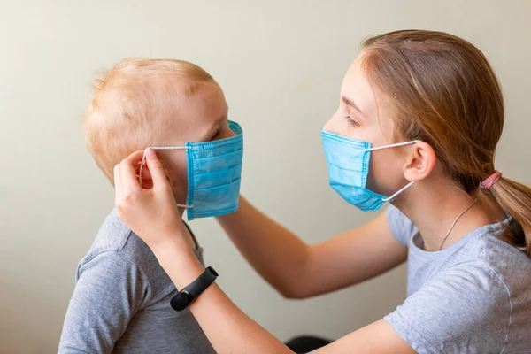 Adolescente Ajudando Seu Irmão Mais Novo Usar Uma Máscara Médica — Fotografia de Stock