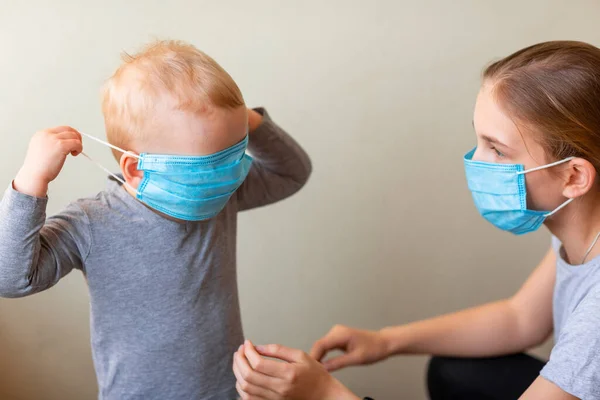 Genç Kız Kardeşinin Tıbbi Maske Takmasına Yardım Ediyor Coronavirus Koruması — Stok fotoğraf