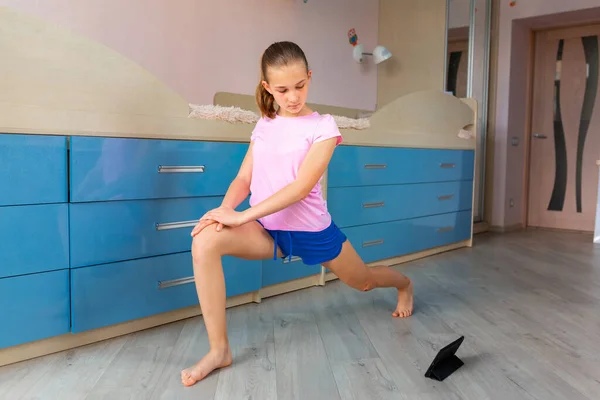 Tennage girl doing fitness gymnastics at home. Gymnastics video tutorial. Gymnastic exercises. Children\'s activity in quarantine during coronavirus pandemic concept