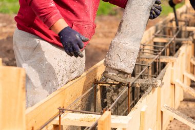 Otomatik pompayla temel çalışmalarına çimento ya da beton döşeyen inşaat işçilerini kapatın. Ev temelleri oluşturuluyor