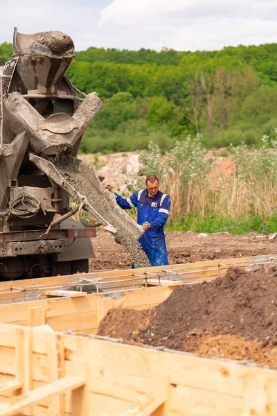 Construction worker laying cement or concrete into the foundation formwork. Building house foundation