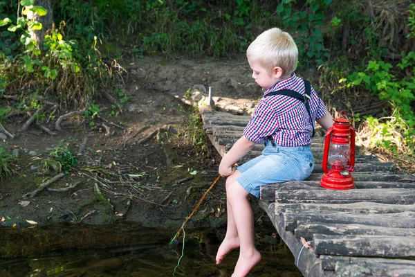 Chłopiec siedzi na drewniany most — Zdjęcie stockowe