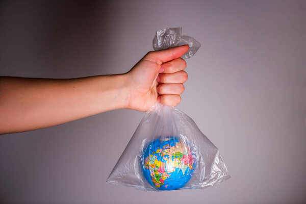 Рука держит пластиковый пакет с глобусом внутри. Эко, экологическая концепция. Ноль отходов
