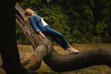 Genç ve güzel bir kadın parkta dinleniyor. Dışarıda dinleniyor.