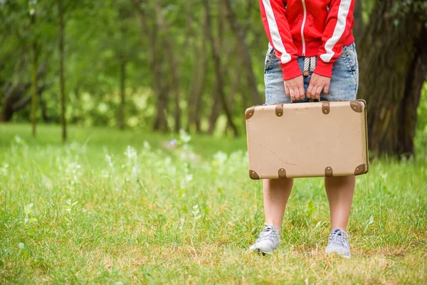 Young person is standing with an vintage suitcase. Photo from the back. Local travel concept