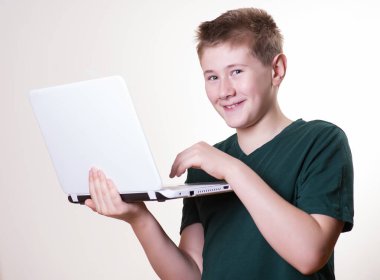 Heyecanlı 10-12 yaşındaki bir çocuk dizüstü bilgisayarını kullanıyor.
