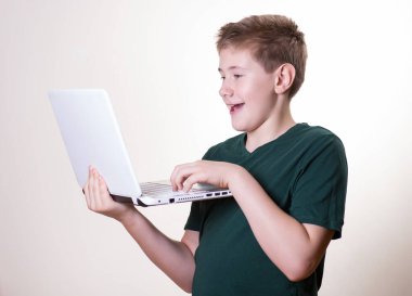 Heyecanlı 10-12 yaşındaki bir çocuk dizüstü bilgisayarını kullanıyor.