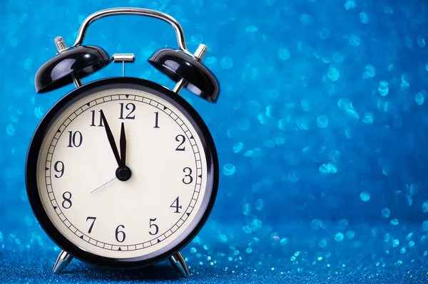 Alarm clock on blue glitter background
