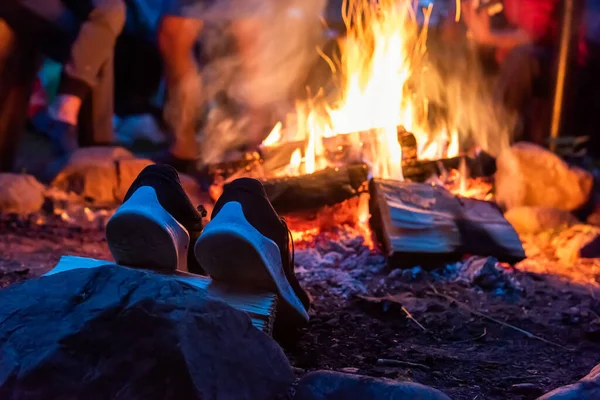 closeup camp fire at the night . A pair of camp shoes is dried near a fire in the forest