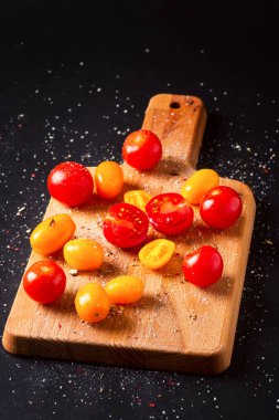 Siyah arka plandaki tahta üzerinde farklı domates tarlaları. Çok renkli domatesler