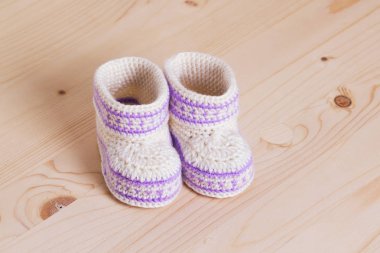 Ahşap arka plan üzerinde Bebek Patikleri tığ