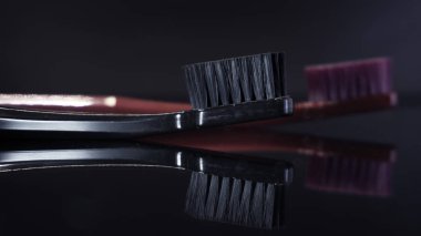 Renkli diş fırçaları koyu arkaplanda izole edilmiş olarak yakınlaşır.