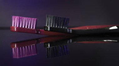 Renkli diş fırçaları koyu arkaplanda izole edilmiş olarak yakınlaşır.
