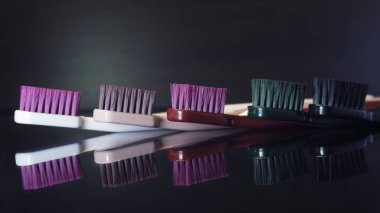 Renkli diş fırçaları koyu arkaplanda izole edilmiş olarak yakınlaşır.