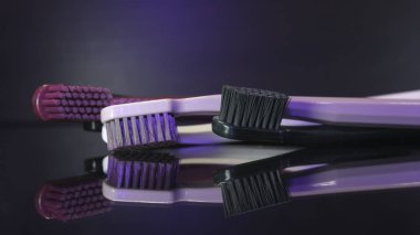 Renkli diş fırçaları koyu arkaplanda izole edilmiş olarak yakınlaşır.