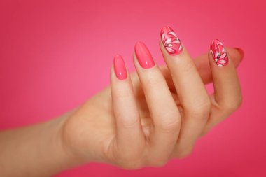 Çiçekli pembe nailart ile kadının tırnakları manikürlü.