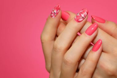 Çiçekli pembe nailart ile kadının tırnakları manikürlü.