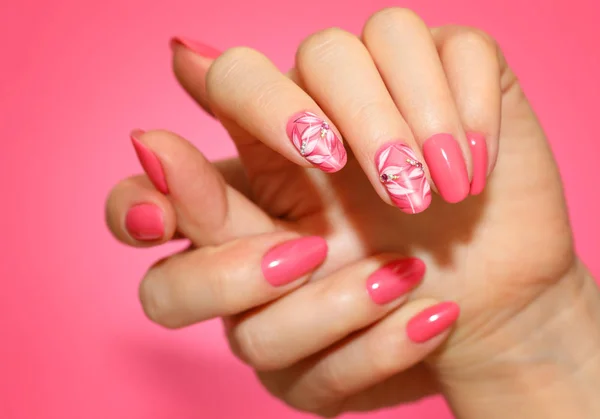 Manicura uñas de mujer con clavos de color rosa con flores . — Foto de Stock