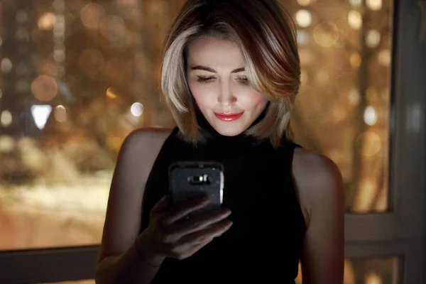 Flicka med smartphone nära fönster — Stockfoto