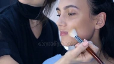 Makyaj sanatçısı için çekici bir genç kadın makyaj uygulamak. 