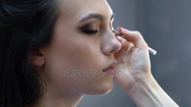 Makyaj sanatçısı için çekici bir genç kadın makyaj uygulamak. 