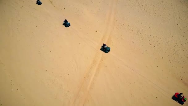Skyline Luftaufnahme junger Männer auf Quad-Fahrrädern über Sanddünen in der Wüste. — Stockvideo