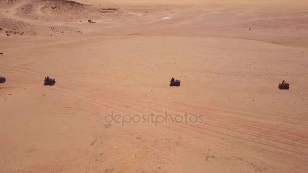 Skyline Vue aérienne de jeunes hommes chevauchant des quads sur des dunes de sable dans le désert . — Video