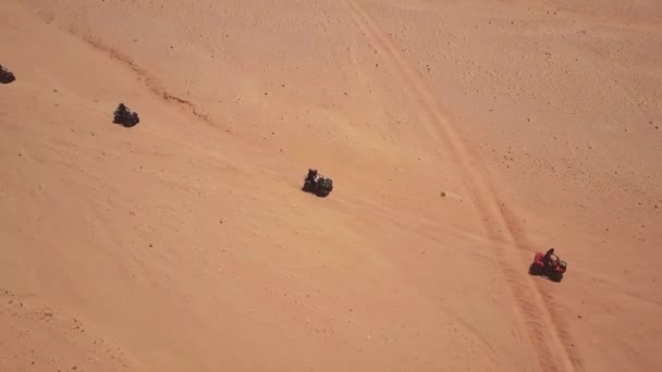 Skyline Vue aérienne de jeunes hommes chevauchant des quads sur des dunes de sable dans le désert . — Video