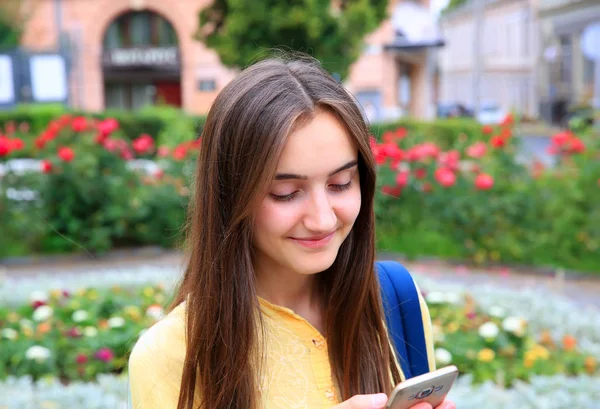 Mooi meisje met mobiele telefoon leest een bericht in de stad. — Stockfoto