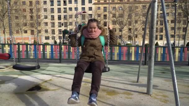 Маленькая девочка с синдромом Дауна веселится на качелях — стоковое видео
