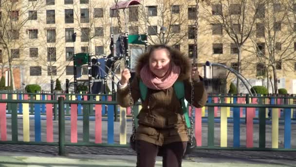 Маленька дівчинка з синдромом Дауна розважається на гойдалках — стокове відео