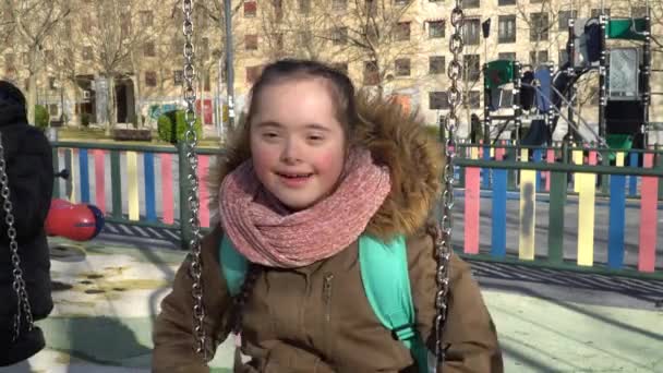 Маленькая девочка с синдромом Дауна веселится на качелях — стоковое видео
