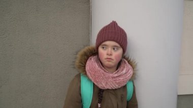 Down sendromlu bir kız dışarıda yürüyor.